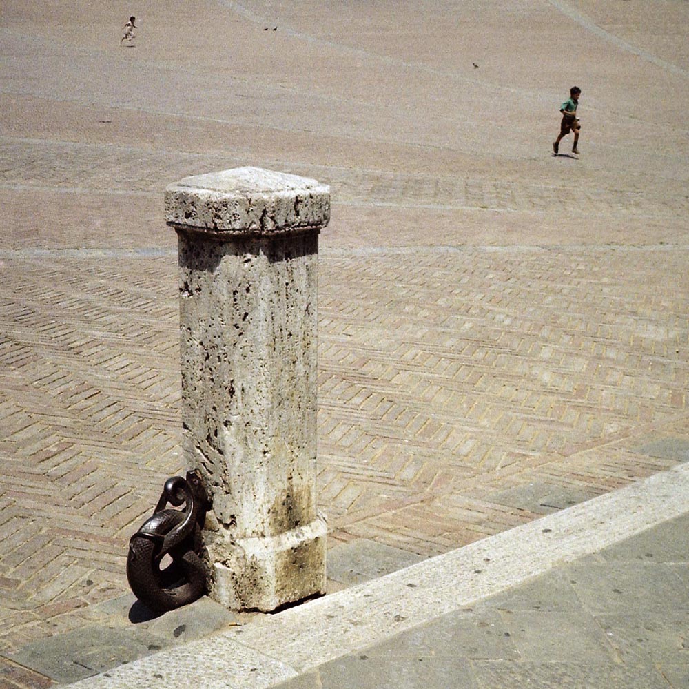 italy italians plazas courtyards children running posts people boys pole link metal concrete pavement white tan black 