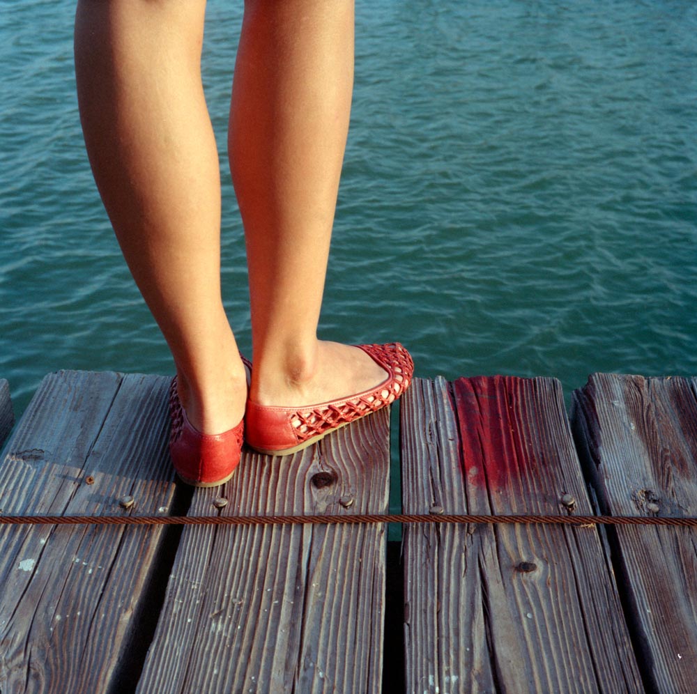 feet legs shoes docks water wooden red paint cable woman calves calf ankle ocean waves ripple green blue brown nature formalism ***
