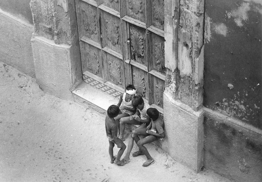 boys boy children wall door grunge rust old people black and white kids step italy gray grey sitting seated talking gossip crowd scenes of italy