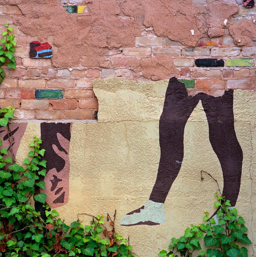 walls plaster stucco murals cracking peeling bricks deconstruction legs feet green tan black white 